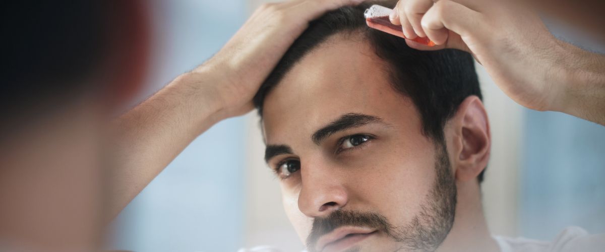 Young man applying hair lotion